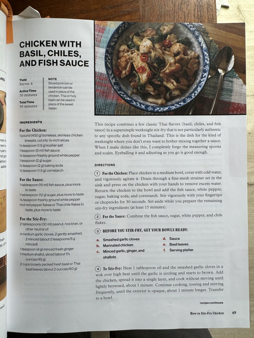 This is a page from a cookbook featuring a recipe titled 'CHICKEN WITH BASIL, CHILES, AND FISH SAUCE'. The recipe yields 4 servings with an active time of 30 minutes and a total time of 30 minutes. At the top of the page, there's a photograph of the finished dish: chicken stir-fry with basil and slices of red chiles in a bowl. The page includes sections on ingredients for the chicken, the sauce, and the stir-fry. It also has instructions for preparation and cooking, with a note explaining that the dish combines classic Thai flavors in a simple stir-fry that isn't particularly authentic to any specific Thai dish. The note suggests that measuring precisely isn't necessary and it's sufficient to adjust the ingredients 'as you go.' To the left of the recipe, there are steps labeled 'BEFORE YOU STIR-FRY, GET YOUR BOWLS READY' with sub-steps from (a) to (f) that include prepping garlic, chicken, ginger, sauce, basil leaves, and a serving platter. Below this, there are steps on how to execute the stir-fry process.